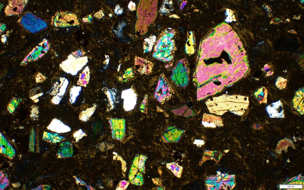 Bright pink, green and purple minerals- pyroxenes, in a dark clay matrix.