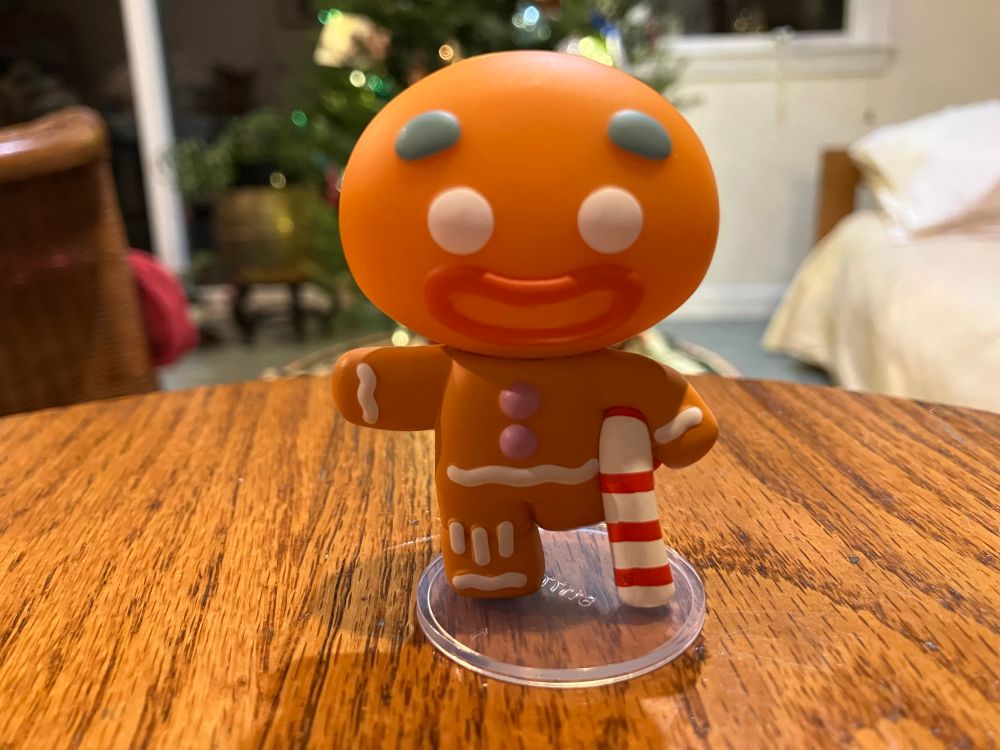 Gingerbread man figure with a candy cane for a leg.