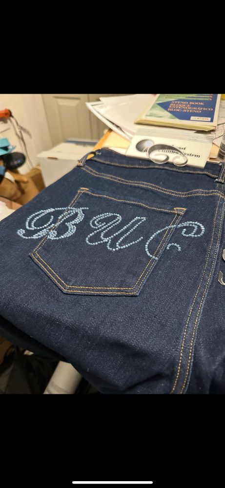 Letters B U and C spelled out in aquamarine rhinestones on the back pocket area of dark wash jeans