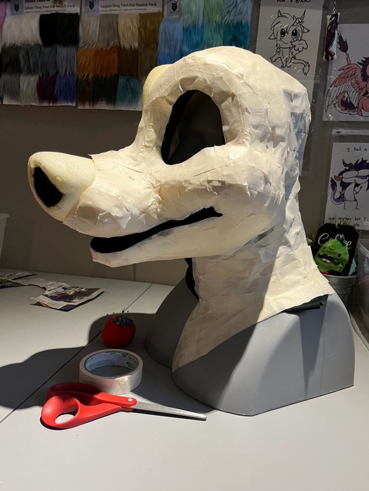 Canine foam fursuit head base on mannequin covered in tape. 
