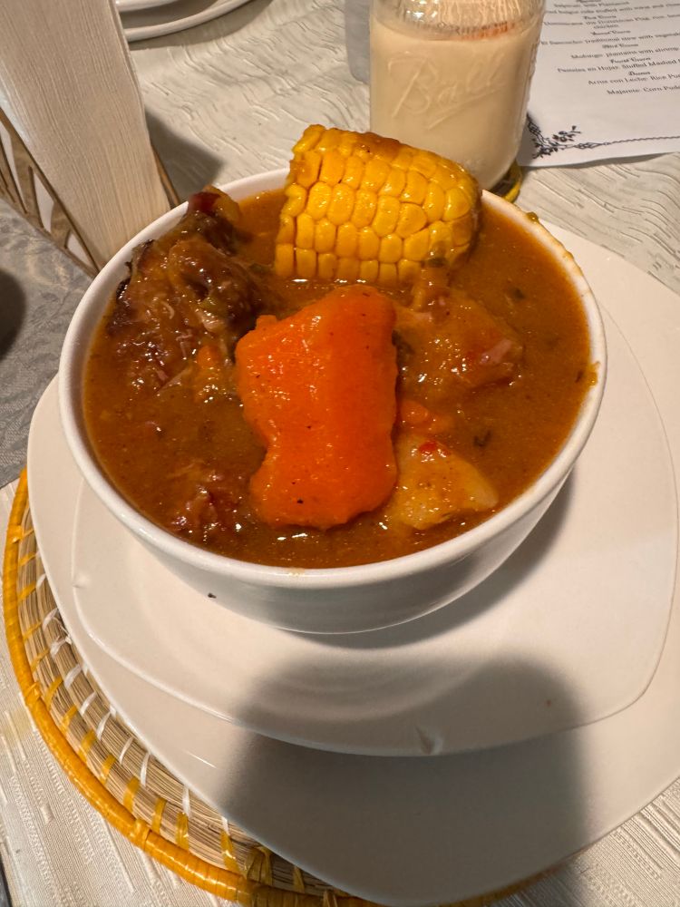 Sancocho in a bowl with a carrot and corn on top. 