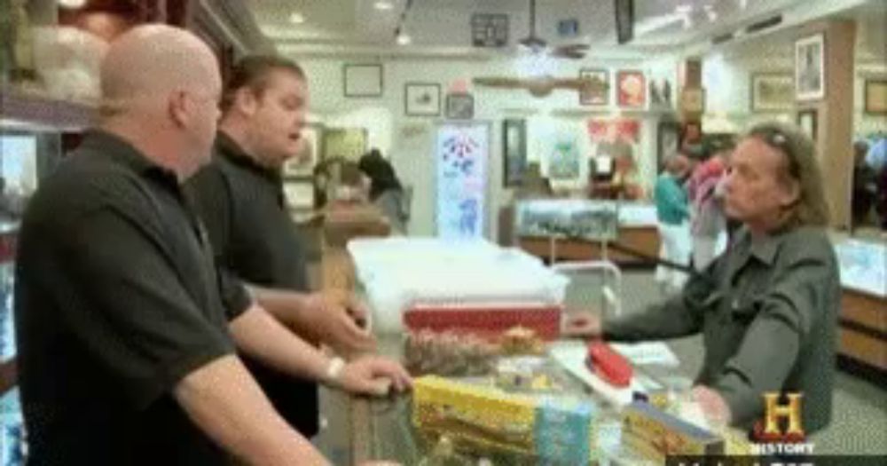 a group of men are standing around a counter in a store with a sign that says history on it