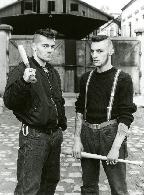 black and white photo of two ridiculously good-looking, skinhead-hunting antifascists holding baseball bats