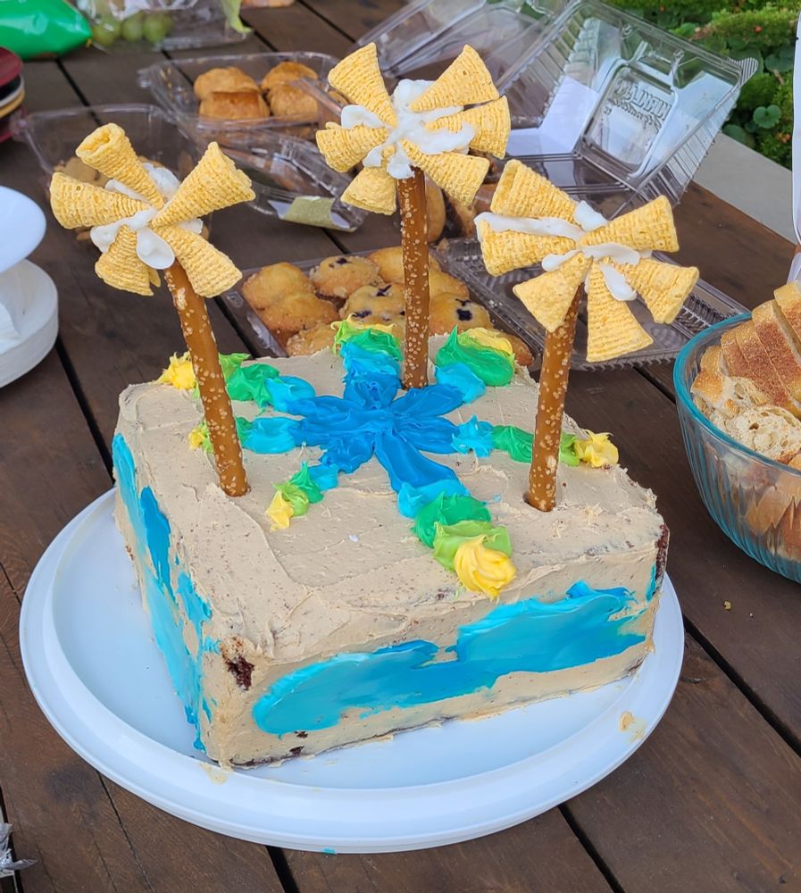 Cake decorated to look like a wind farm. The wind turbines are made from a pretzel stick with Bugle snacks arranged to look like turbine blades.