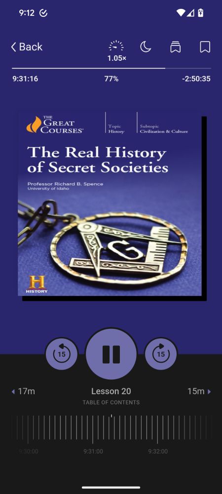 A screenshot of the Libby app showing the audiobook/series of lectures in progress, The Real History of Secret Societies, published by The Great Courses. Lecturer is Professor Richard B Spence of the University of Idaho. The background color is blue purple. The book cover is a photo of a silver masonic pendant comprising a square and compass with a large G in the center.  