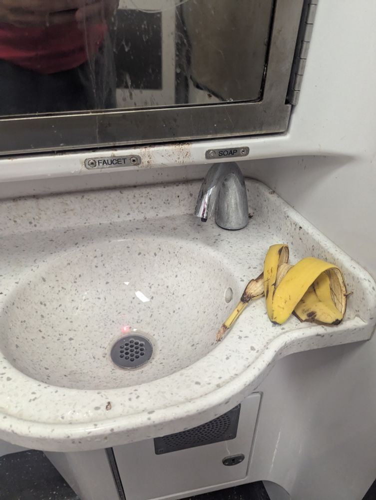 An LIRR bathroom sink with a banana peel next to it 