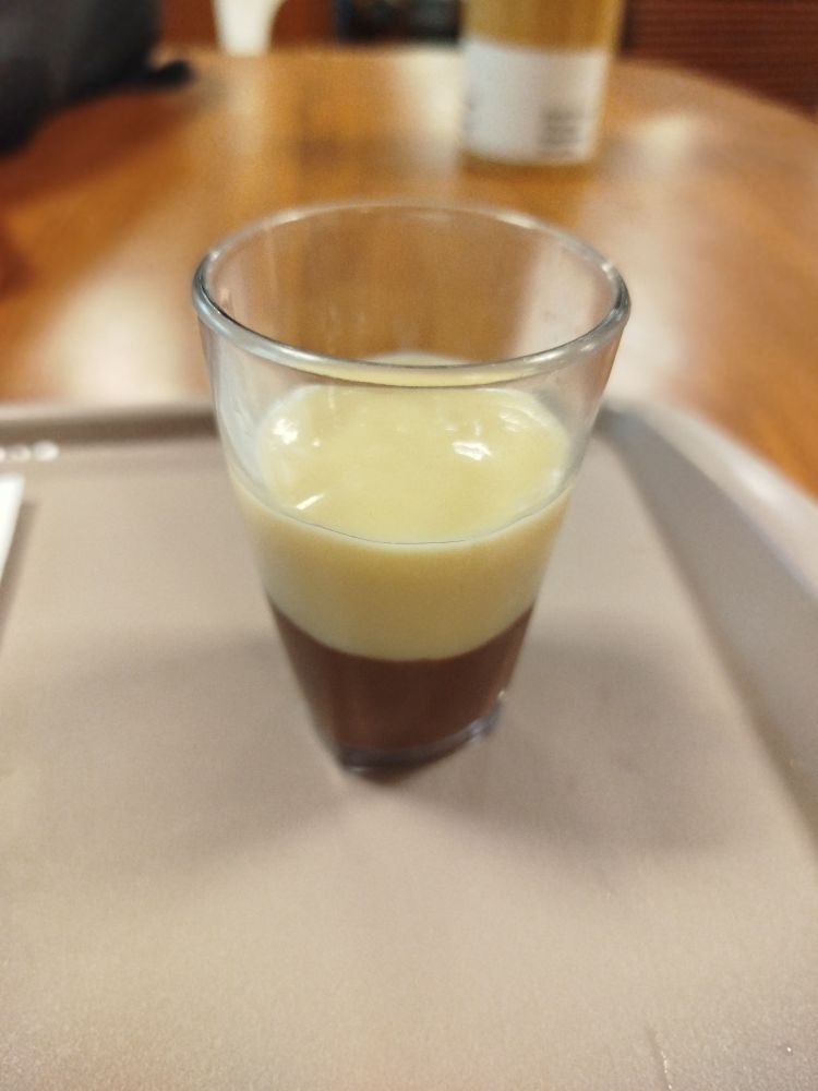 Copinho de brigadeiro de colher com chocolate ao leite embaixo e chocolate branco em cima.