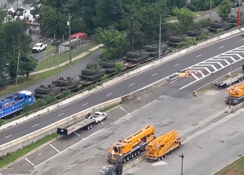 Aerial view of a freight train carrying dozens of tanks rolling through a neighborhood in DC