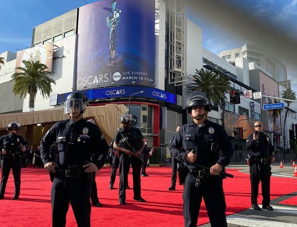 A phalanx of LAPD riot police officers with batons drawn stands on the Oscars red carpet
