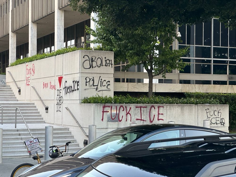 Stairs to federal building covered in graffiti that says "Fuck ICE", "fuera ICE", and "IDF/LAPD/ICE 🔻" with a red triangle over it