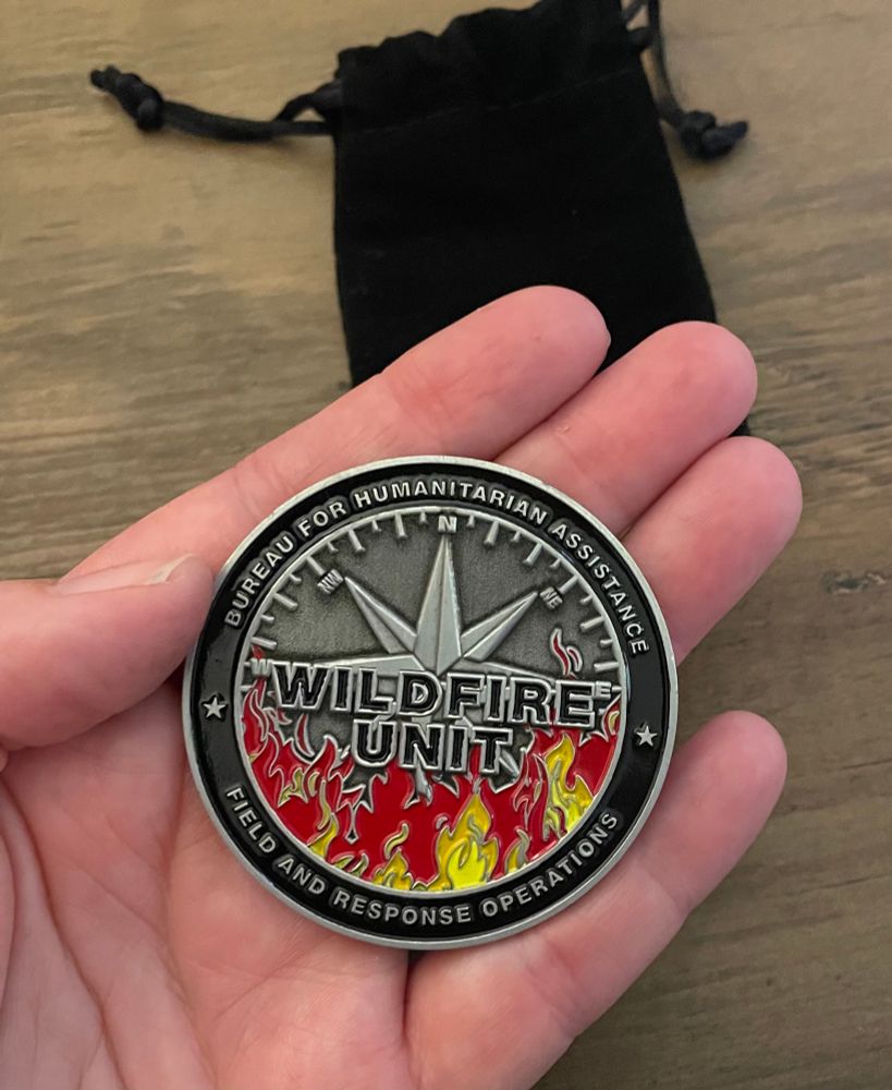 Wildfire Unit coin - a challenge coin - from the Bureau For Humanitarian Assistance of the USAID. Front side featuring a compass rose and flames. 