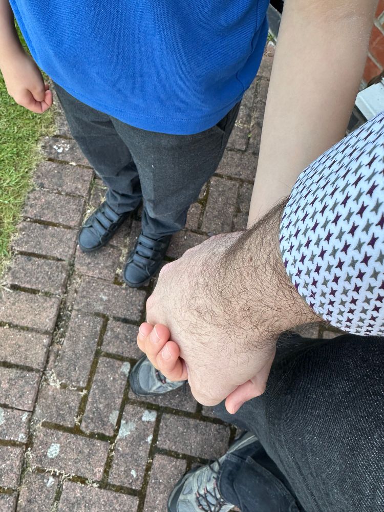 Me holding my sons hand on the school drop off 
