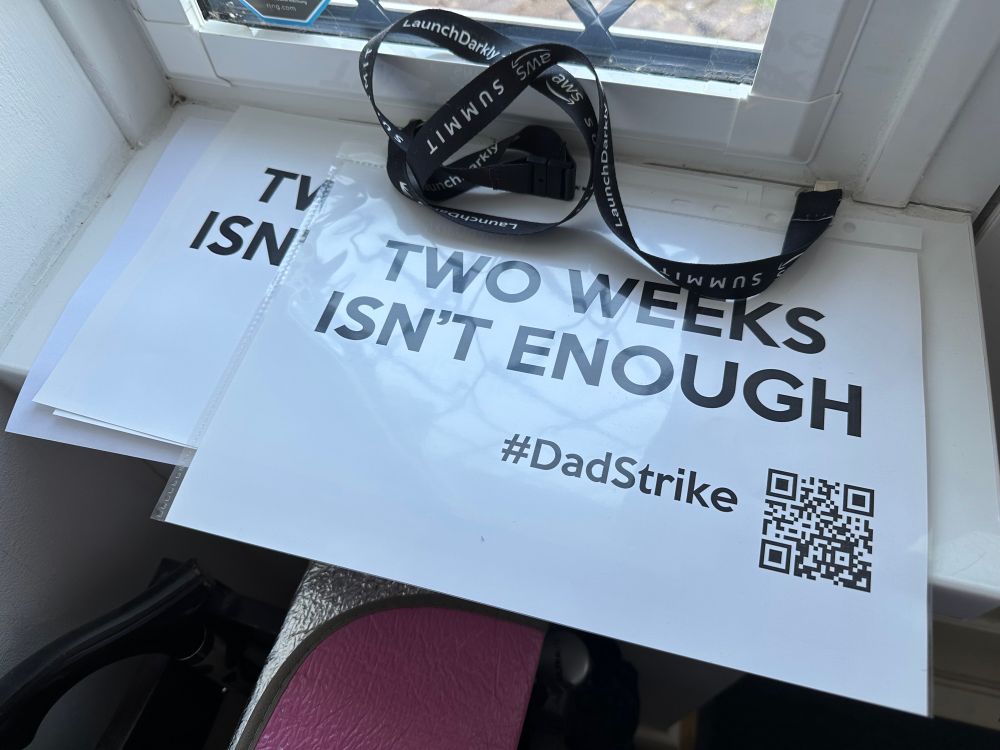 Placards on a windowsill stating “two weeks isn’t enough” and hashtag Dad Strike with a QR code 