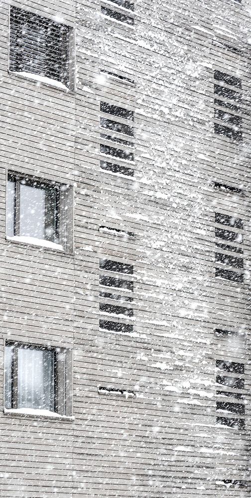 Schneefall und haftender Schnee reduzieren diese holzverkleidete Fassade zu einer Textur
