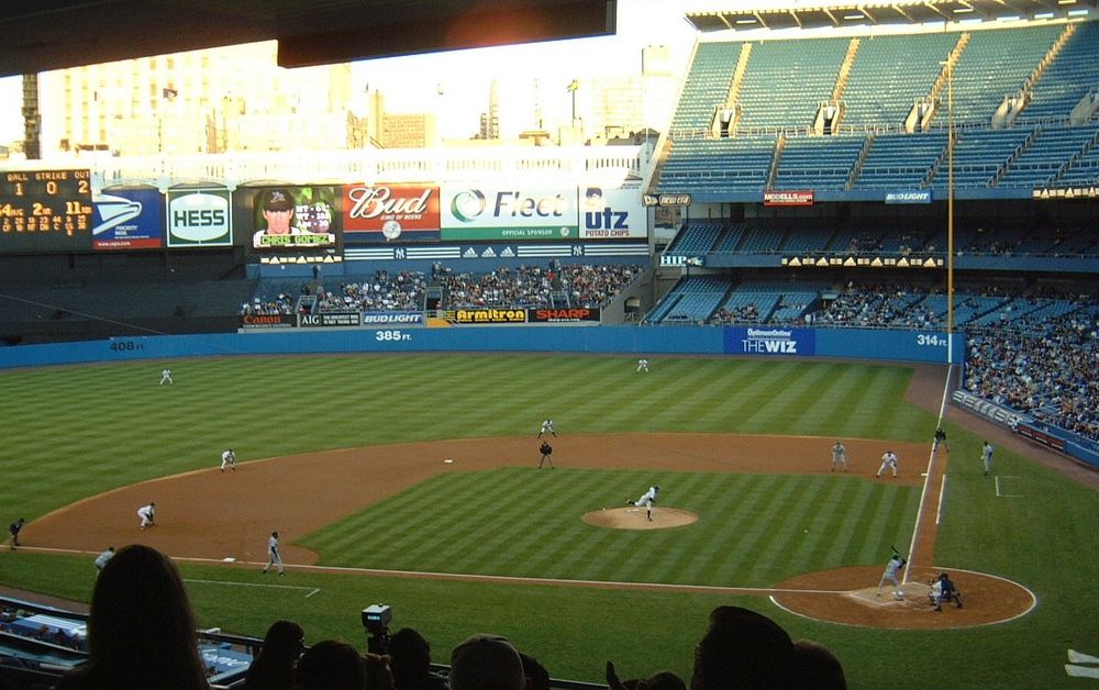 Yankee Stadium on Opening Day, 2002. A wide shot of the field from high up in the lower deck on the third base side so we can see all of right field, including the advertisements on the wall behind the bleachers, of which the Utz sign is the furthest right, in about straightaway right field.