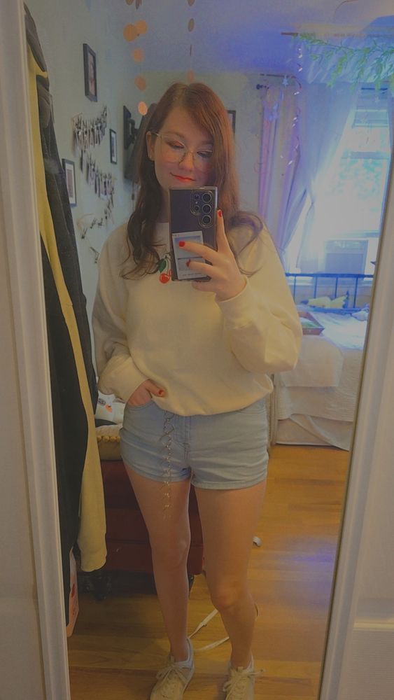 Me in a shirt with a cherry on it, wearing red eyeshadow with red lip gloss. Also red nail polish. And light jean shorts, with white sneakers. 
