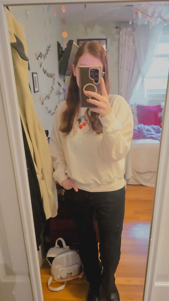 Me in a white sweater with a small cherry in the center at the top, ans black jeans