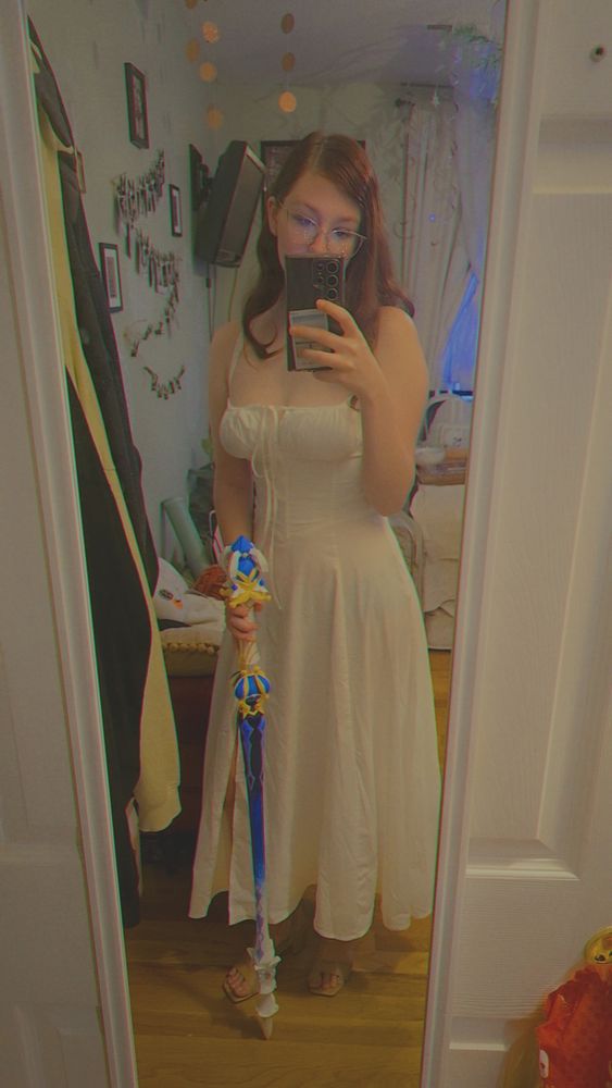 Me in a white dress holding a blue and gold sword