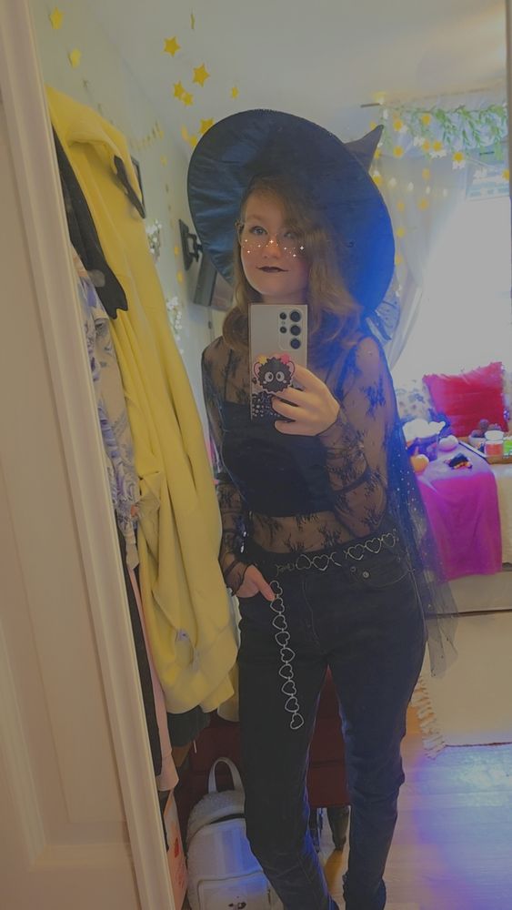 Me in a transparent top with a tank under it, wearing black jeans as well. Ive got a black witches hat on