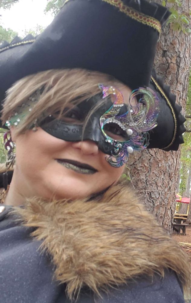 Myko in a pirate hat, peacock mask, and fur collared cloak at a renissance festival