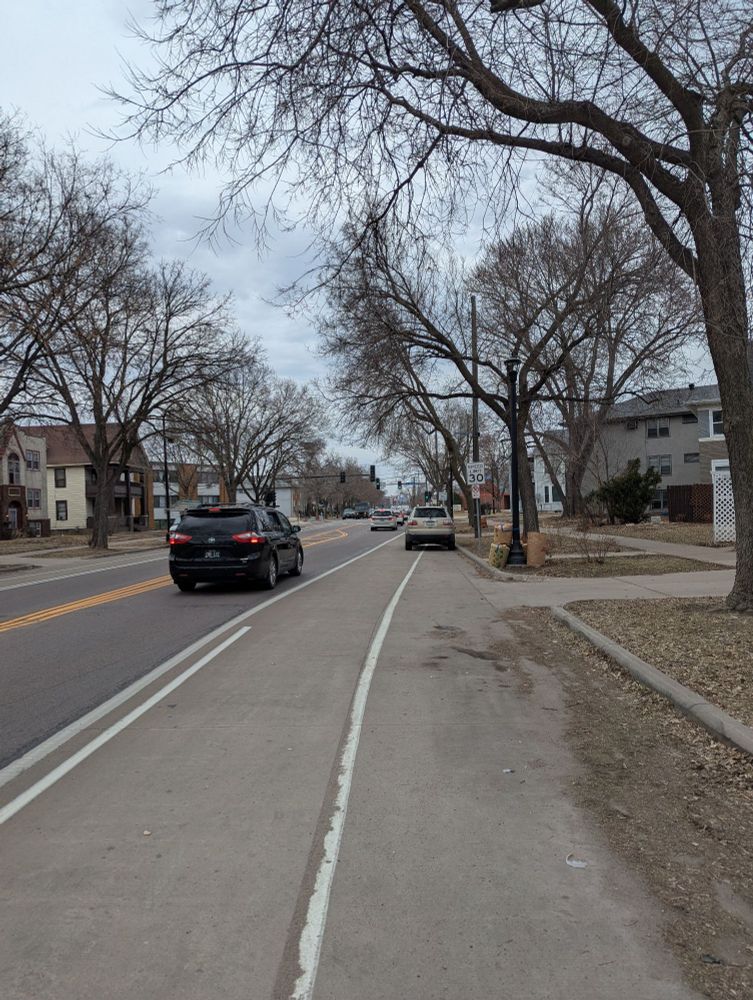 A photo of a car parked illegally in a bike lane despite there being open parking they could use nearby 