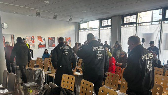 Photo des flics faisant irruption dans la salle où se tenait la conférence.