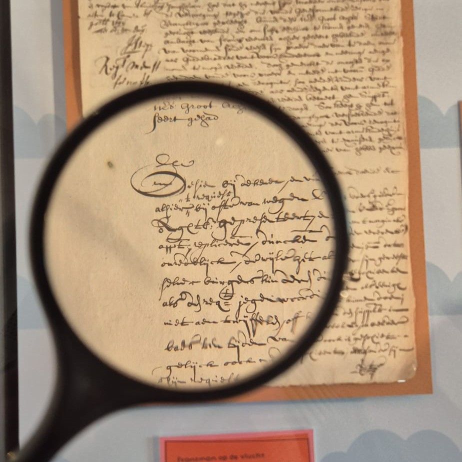 Zwart vergrootglas over een Middeleeuwse tekst in een vitrine