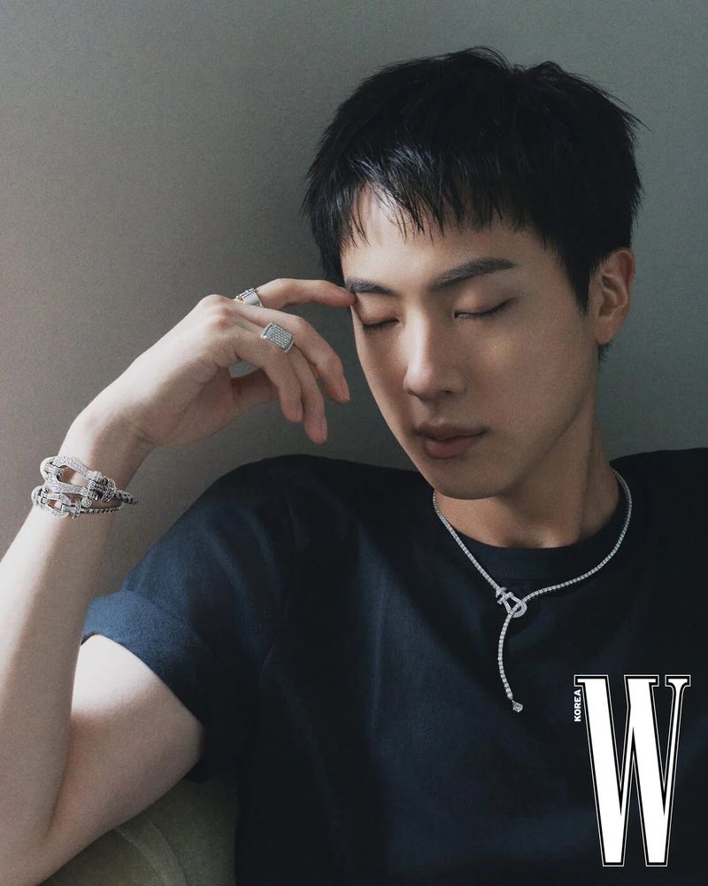Kim SeokJin of BTS in his latest pictorial for W Korea wearing lovely bracelets, and necklace that drapes down from his neck. Jin has adopted a thinker pose, with his eyes closed, and finger to his eyebrow.