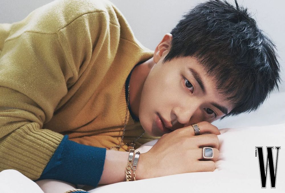 Kim SeokJin from BTS laying on his side in W Korea pictorial looking majestic with tasteful rings and bracelets. Image shows from shoulders to head.