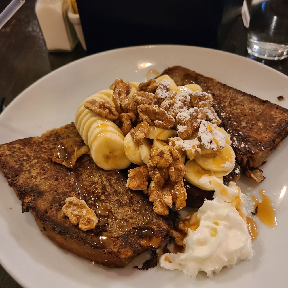 A picture of banana french toast with pecans and caramel syrup.