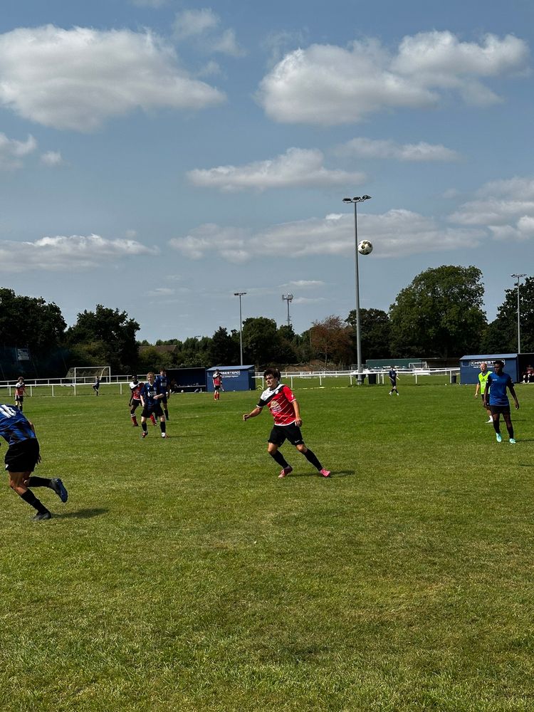 Football (Sunday league friendly), green pitch and blue sky. 