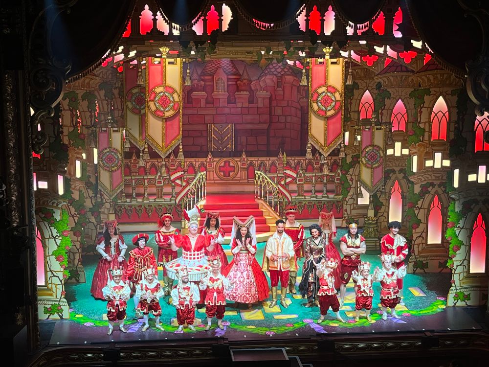 The cast of Snow White at the finale. ‘The seven’, five dancers, Wicked Queen, Nurse Nellie the dame, Henchman from Gladiators, Prince Charming, Herman, Muddles and Snow White. All in red and white on a red and gold wedding scene set. 