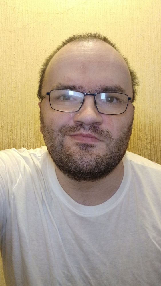 Me against a beige wall wearing a white tee shirt 