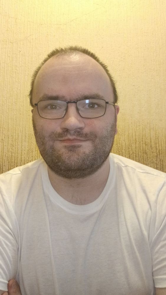Me against a beige wall wearing a white tee shirt. 