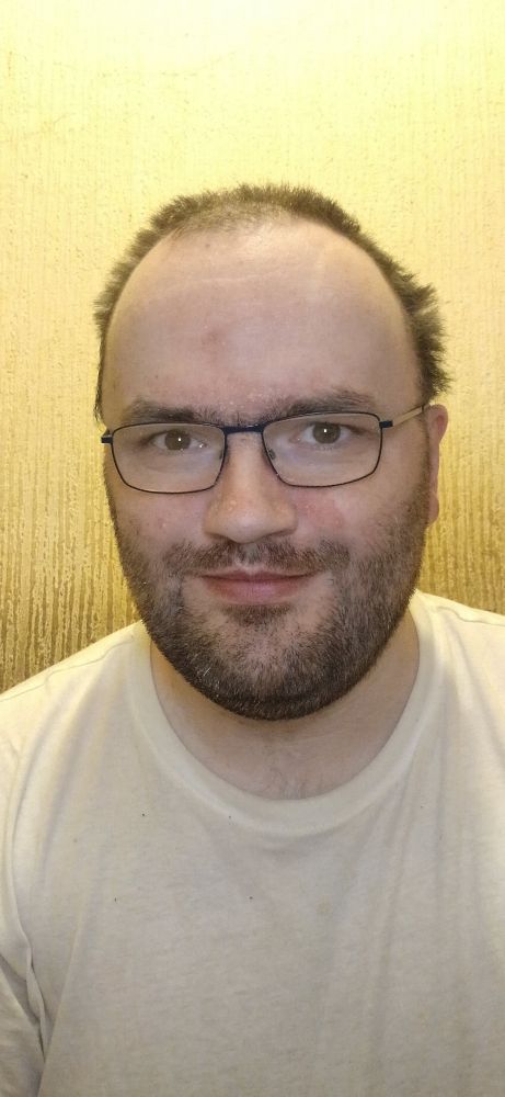 Me against a beige wall wearing a white tee shirt. 