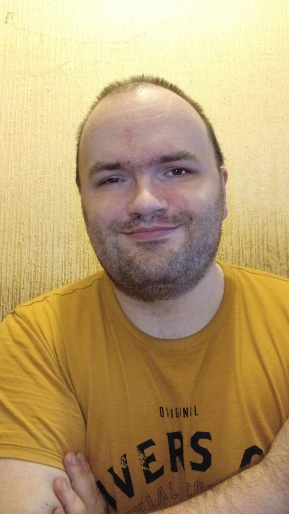 Me against a beige wall wearing a orange tee shirt 
