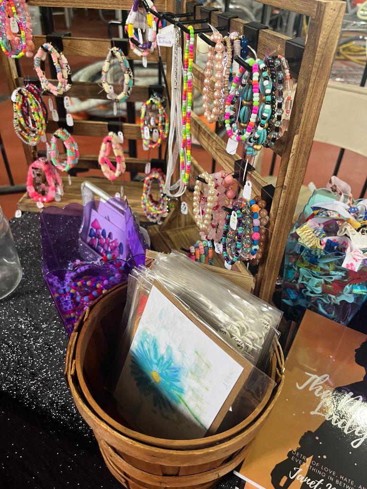 Bracelets, books, postcards, hair ties, necklaces, stickers for sale.