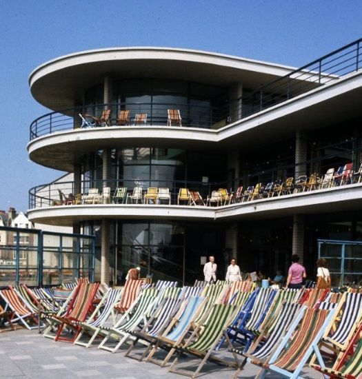 A colour photograph of the De La Warr pavilion with striped deckchairs in front