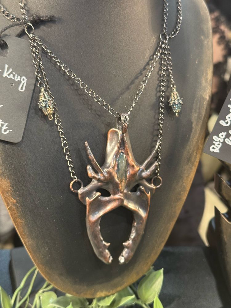 Medallion resembling the helmet of the Witch-king of Angmar, made out of bones with copper plating