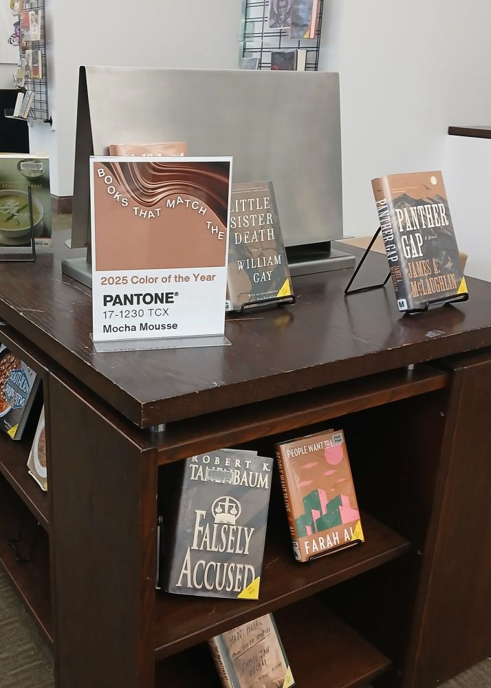 display at the library with placard: "Books that match the 2025 Color of the Year, Pantone 17-1230 TCX 'Mocha Mousse'," which is a reddish light brown.