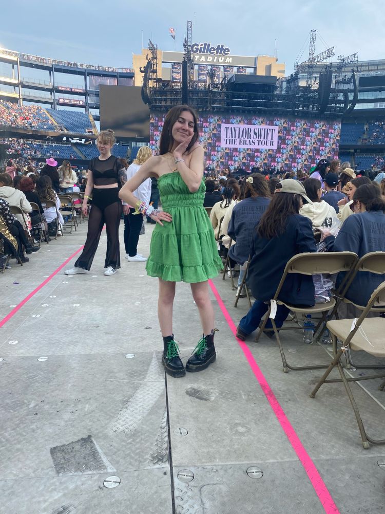 cynthia at eras tour gillette night one on the floor in one of the isles. i am wearing a green strapless dress and black platform docs with laces that match my green dress.