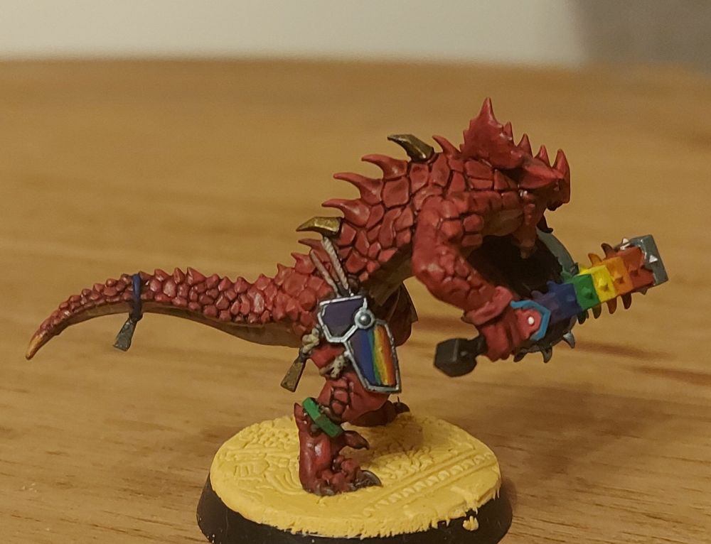 A photo of a pink Saurus Warrior miniature with LGBT themed gears and equipment !
