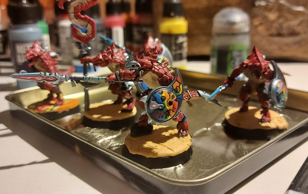 A leader of a pink LGBT+ Saurus Warrior unit is seen ordering his fellow lizards to move to the direction he's pointing at with their spear.

Most certainly to protect other marginalised people. Or to bash Fa-I mean Chaos followers.