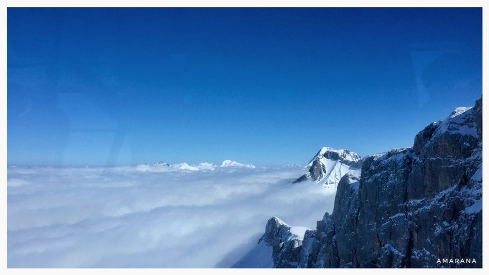 Blauer Himmel über den Wolken, Bergspitzen, teilweise schneebedeckt 