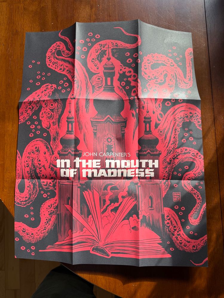 Movie poster in red and black. The foreground shows a book with flipping pages, with a three towered onion domed church behind it. Behind the church are a large number of writhing tentacles and eyes staring out of the darkness. 