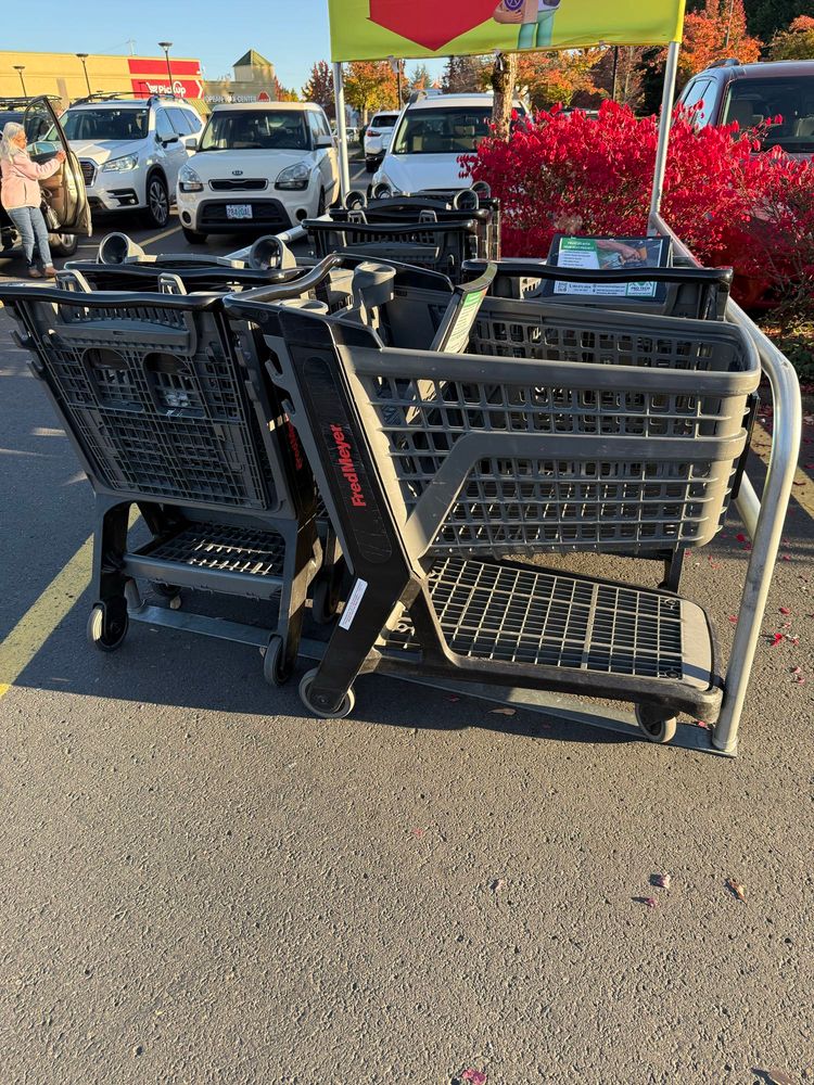 Shopping cart corral at a grocery store. Most carts are placed in the normal way, nose end in first. The cart on the front right is somehow placed perpendicularly to the other carts. 