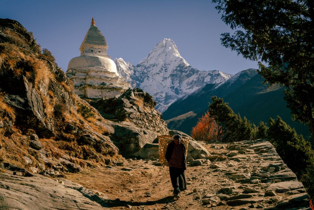 A woman walks into front of a Buddhist Stupa with Ama Dablam in the background 