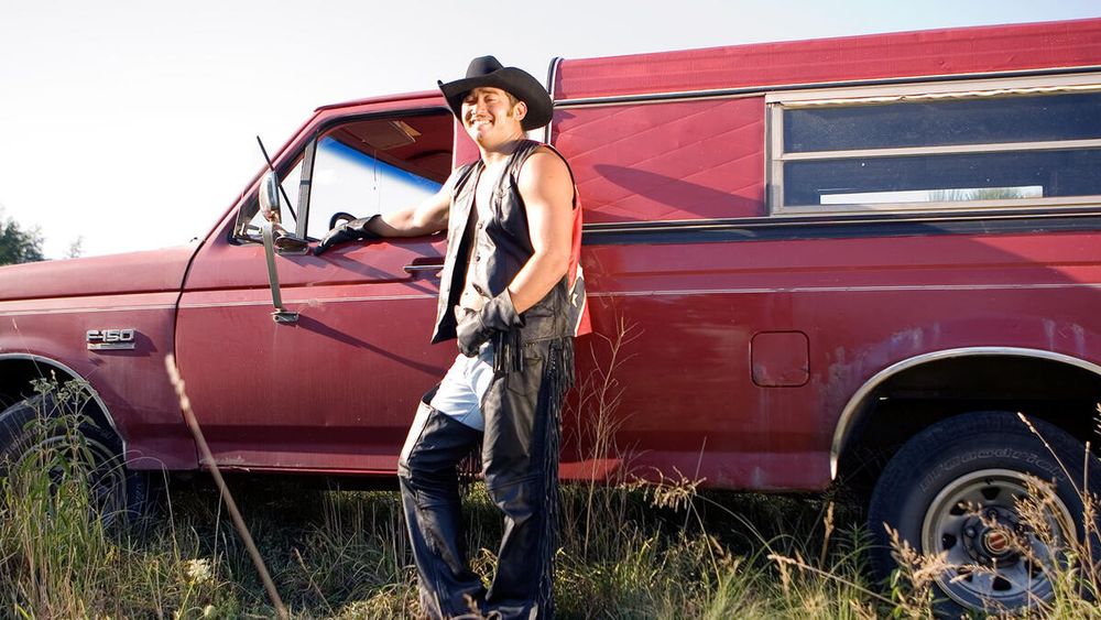 Jimmy wang yang in leather chaps and vest posing next to his truck