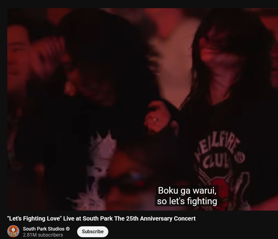 a crowd shot of some girls with black hair and dark makeup headbanging to "Let's Fighting Love" on a youtube video uploaded by South Park Studios.  The lyric being sung at the moment is "Boku ga warui, so let's fighting".