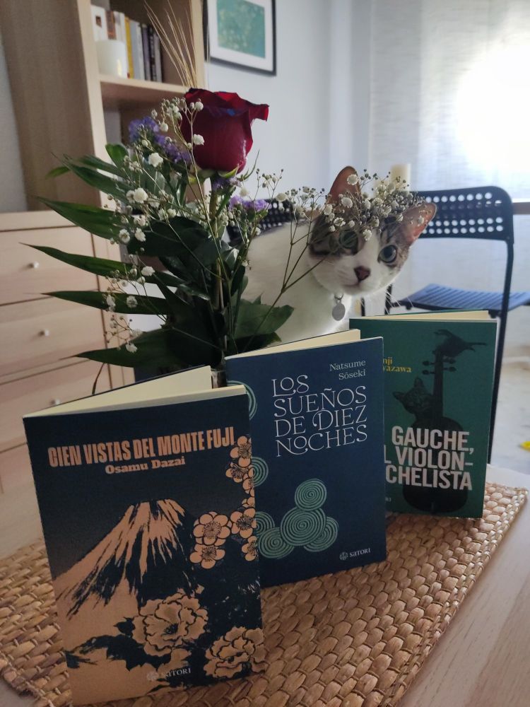 En la imagen aparecen 3 libros en primer plano ("Cien vistas del Monte Fuji", "Los sueños de diez noches y Gauche, el violonchelista". Tras los libros aparece una rosa de Sant Jordi con su espiga. Todo acompañado por Sōseki el gato, asomándose por atrás 